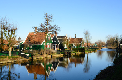 This is a wide angle view of residential homes and a bridge over water in the pituresque town village of Zaanse Schans on a winter day.