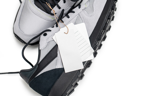 Close-up of blank footwear tag on the grey sports sneakers isolated on white background