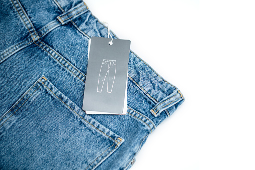 Denim jeans and grey clothing tag isolated on white background.