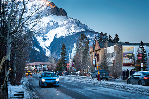 Banff, Alberta, Canada - March 16, 2023: People and cars in downtown shopping district early evening