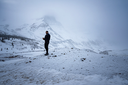 Alberta, Canada - March 25, 2023: Tourist explores uneven terrain landsacape o a foggy day on the Columbia Icefield Parkway in winter between Jasper and Banff