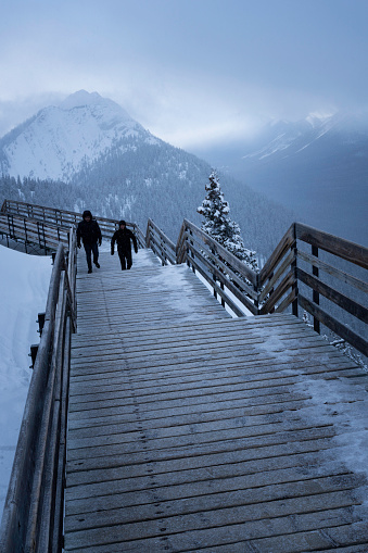 Banff, Alberta, Canada - March 26, 2023: Two people walking up the boardwalk to the Cosmic Ray Station on Sanson's Peak, Sulphur Mountain  at Banff Gondola