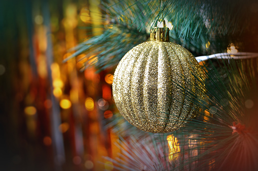 Christmas decoration - Closeup of one golden disco ball hanging in tree with lights in the backdrop