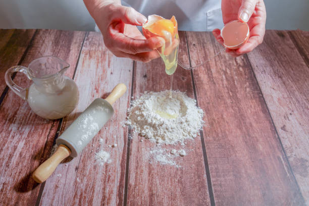 istock woman breaking an egg, pouring it over flour 1849012316