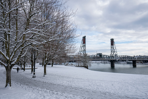 Waterfront park along the Willamette River in downtown Portland, Oregon, after heavy snowfall on a cold winter day. The Hawthorne Bridge is seen in the background.