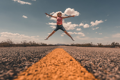 A young female jumping in mid-air against a backdrop of Route 66 in the United States