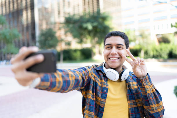 istock Smiling hispanic college student gesturing success while taking selfie outdoors 1849045857