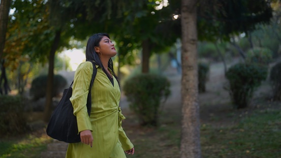 A multiracial woman is enjoying strolling in a public park.