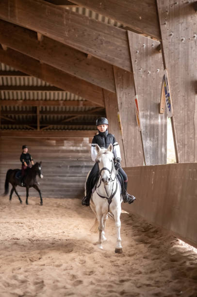 istock beautiful young girl on her white pony during her riding lesson 1849076781