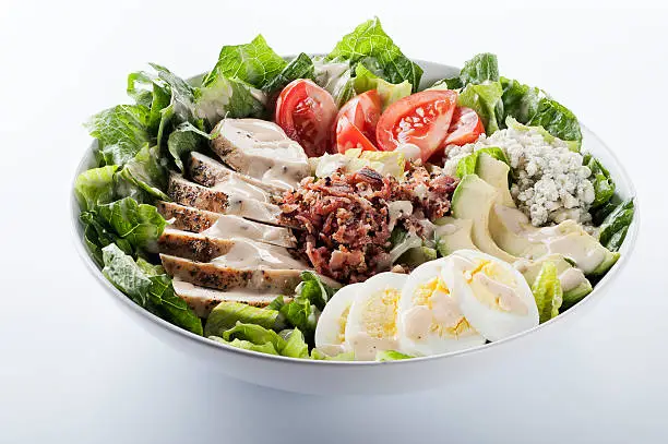 "SEVERAL MORE IN THIS SERIES. Fresh salad of romaine greens, sliced chicken breast, tomatoes, bacon, avocado, boiled egg, and blue cheese.   Isolated on white with clipping path."