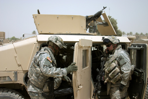 A U.S. Soldier communicates with a radio mounted in an armored HMMWV.