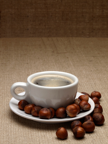 Cup of freshly brewed coffee with elements of flavorings. Hazelnut or filbert