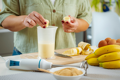 Close up of woman hands preparing healthy banana smoothie