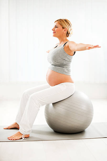 красивая беременная женщина, делать упражнения - human pregnancy prenatal care relaxation exercise ball стоковые фото и изображения