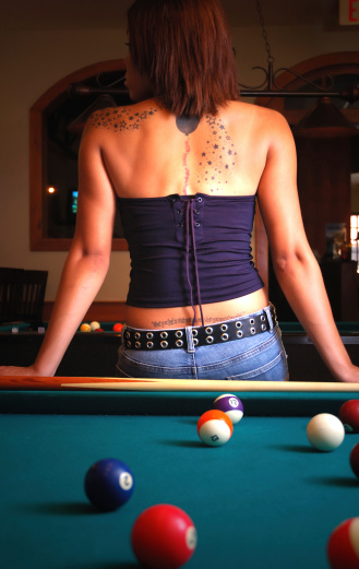 Beautiful woman with intriguing tattoes leaning on a pool table with her back to the camera. Images of Women: