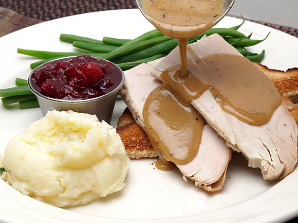 Hot Turkey Sandwich "Open Face turkey sandwich with green beans, cranberry sauce and mashed potatoes with gravy pouring over turkey breast meat." gravy stock pictures, royalty-free photos & images