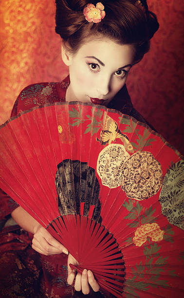 istock Asian beauty peeking out from behind a fan 184915281