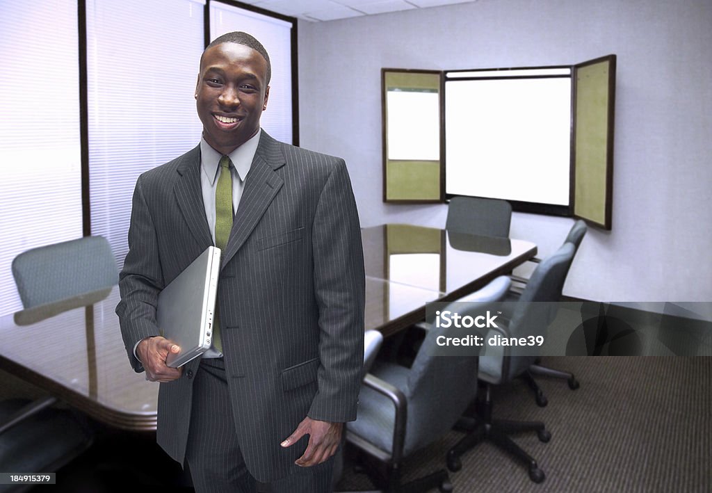 waiting for the meeting An African American businessman holding a laptop computer in a conference roomMore business shots with this model: Adult Stock Photo