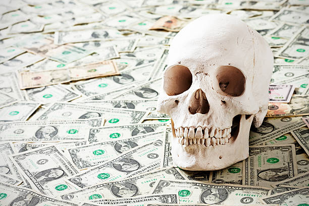istock Money and mortality: human skull on many dollars 184915493