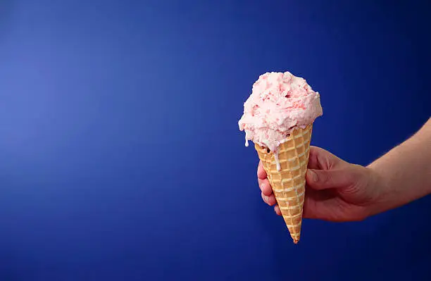 Photo of Strawberry Ice Cream Cone on Blue with Space for Copy