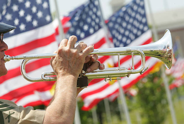 Bugler with american flags Bugler playing taps in front of American Flags bugling photos stock pictures, royalty-free photos & images