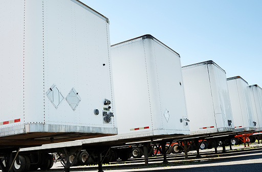 Row of white semi truck trailers on a clear blue sky. Check my transportation lightbox for more trucks.