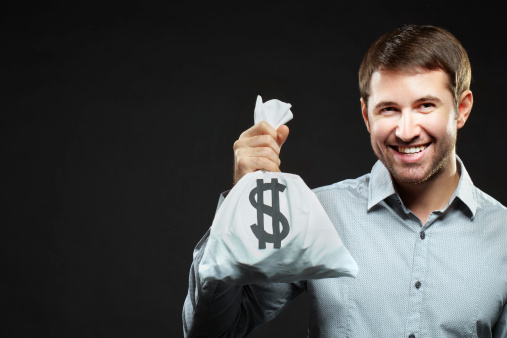 Happy young man holding money bag and looking at camera