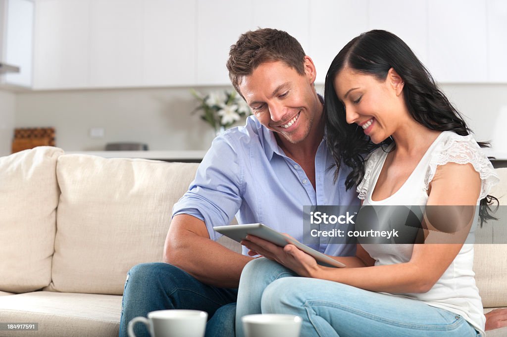 Uśmiechnięta para za pomocą cyfrowego tabletu - Zbiór zdjęć royalty-free (20-24 lata)