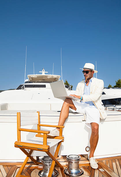 Businessman on board of the yacht. Relaxing. Using laptop. stock photo