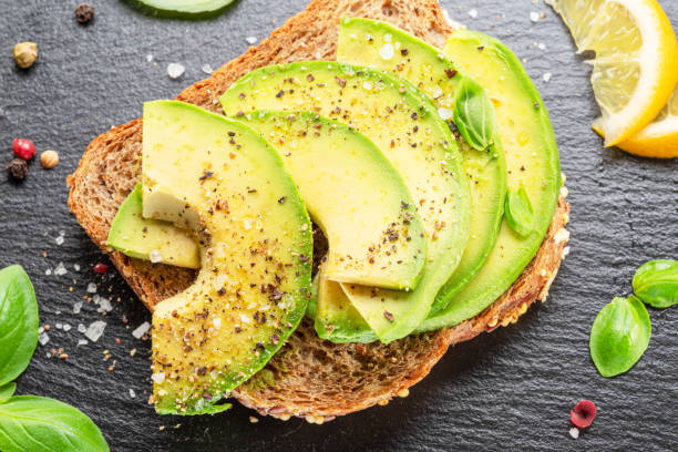 istock Avocado toast - bread with avocado slices on natural slate serving board. Top view. 1849183690