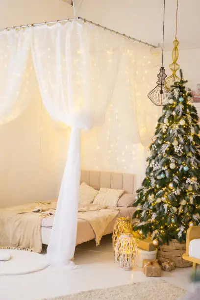 Bedroom in bright colors, decorated for the Christmas holidays. A four-poster bed next to a Christmas tree