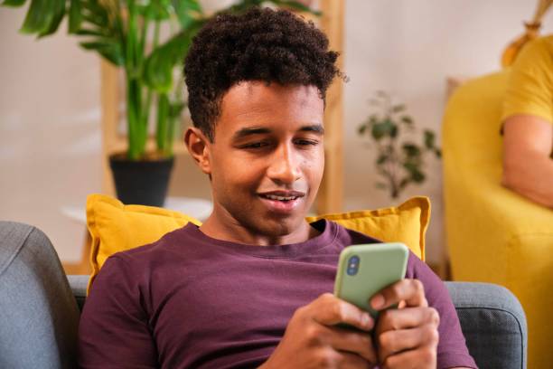 istock Young Black man using his smartphone laying on the sofa at home. 1849198498