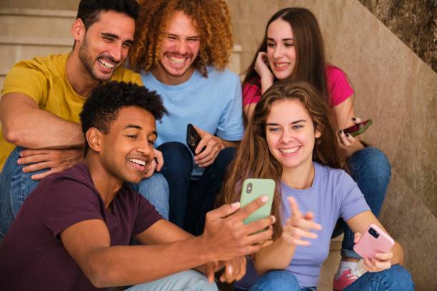 istock Five friends laughing and joking while looking at their phone at stairs. 1849201686