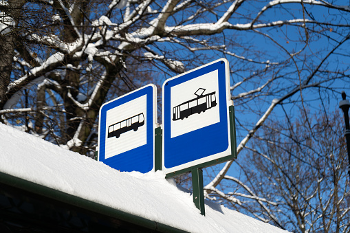 Tram and bus stop information road traffic sign in Poland. Public transport icons signs, tramway and coach autobus info plate. A stand, shelter, or booth shed covered in snow on a cold winter day.