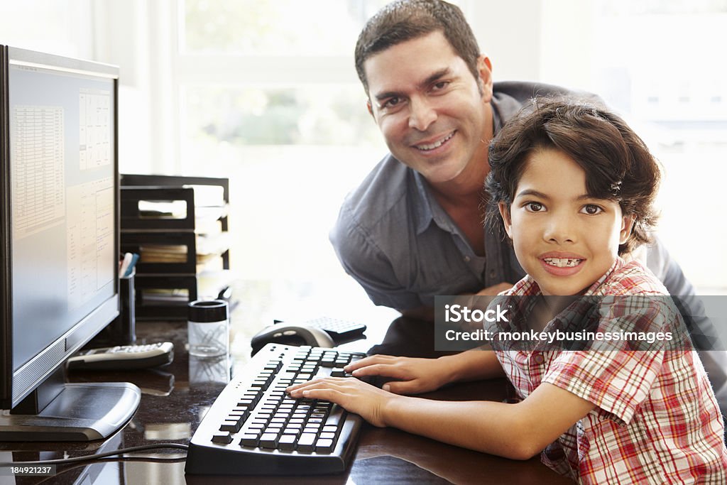 Hispanic father and son using computer at home Hispanic father and son using computer at home smiling towards camera 40-49 Years Stock Photo