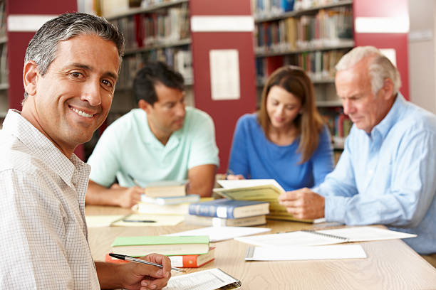 istock Adult students working together in a library  184921416