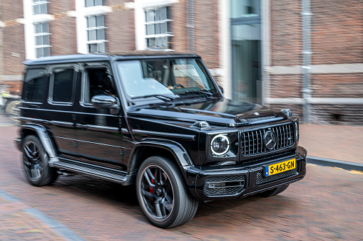 MERCEDES-BENZ AMG G 63 SUV driving fast on the street in Zwolle. The Mercedes-AMG G 63 is a high-performance luxury SUV produced by Mercedes-AMG, the high-performance subsidiary of Mercedes-Benz. The Mercedes-AMG G 63 is known for its powerful performance, distinctive design, and a blend of luxury and off-road capability.