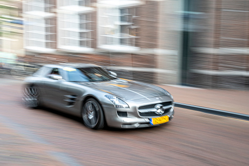 Mercedes-AMG SLS sports car parked in a square in the city of Zwolle during a sunny summer morning. People in the background are looking at the cars.