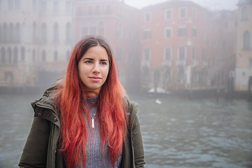 Portrait of beautiful young woman standing by the Grand Canal, enjoying winter break in Venice, Italy