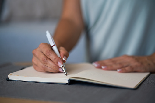 Close-up of unrecognizable woman hand writing on notebook