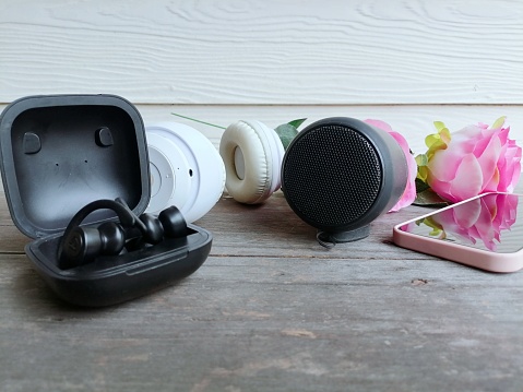 Headphones and black bluetooth speaker on table wood background