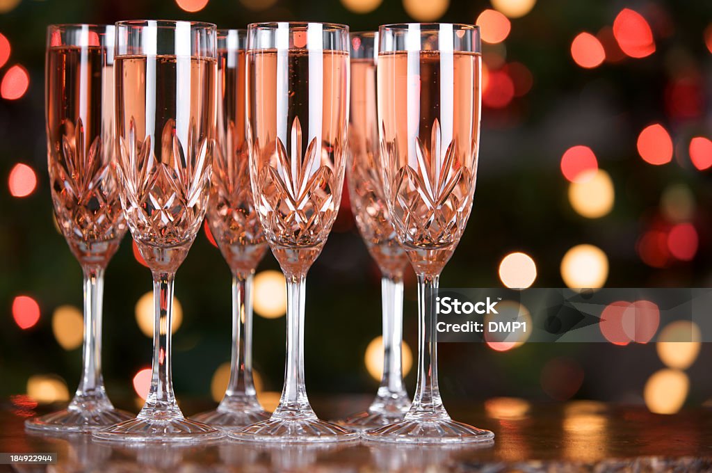 Glasses of pink champagne with coloured defocused lights in background Glasses of pink champagne lined up at a celebration with defocused multi coloured fairy lights in the background. Shallow DOF. One of a series of images. Champagne Stock Photo