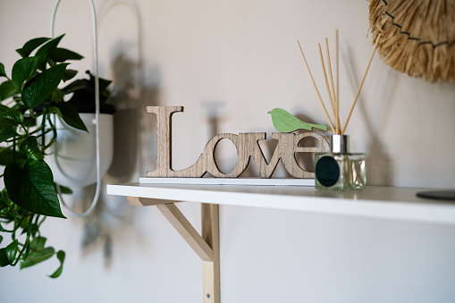 Sign with love and fragrant sticks against wall