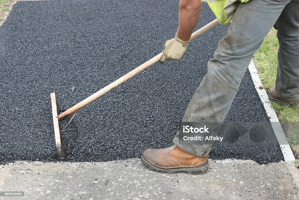 Tarmac layer a shot of a workman laying tarmac by hand Asphalt Stock Photo