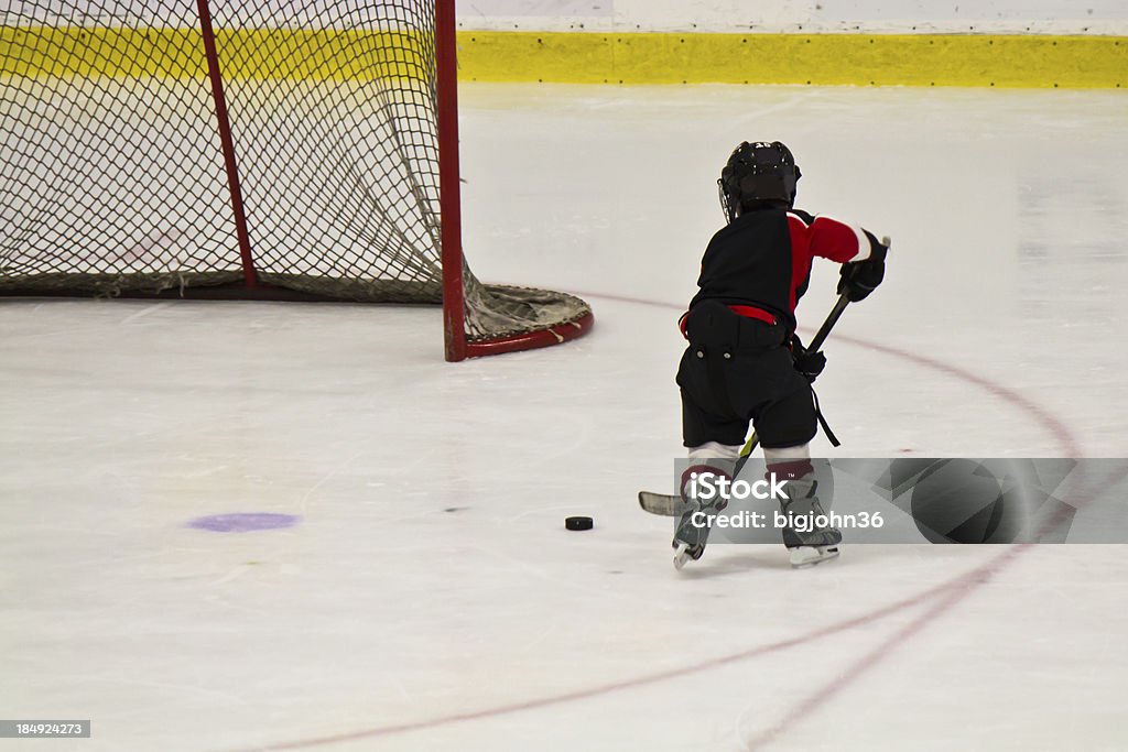 Ребенок, катание на коньках и играть в хоккей в арена - Стоковые фото Ребёнок роялти-фри