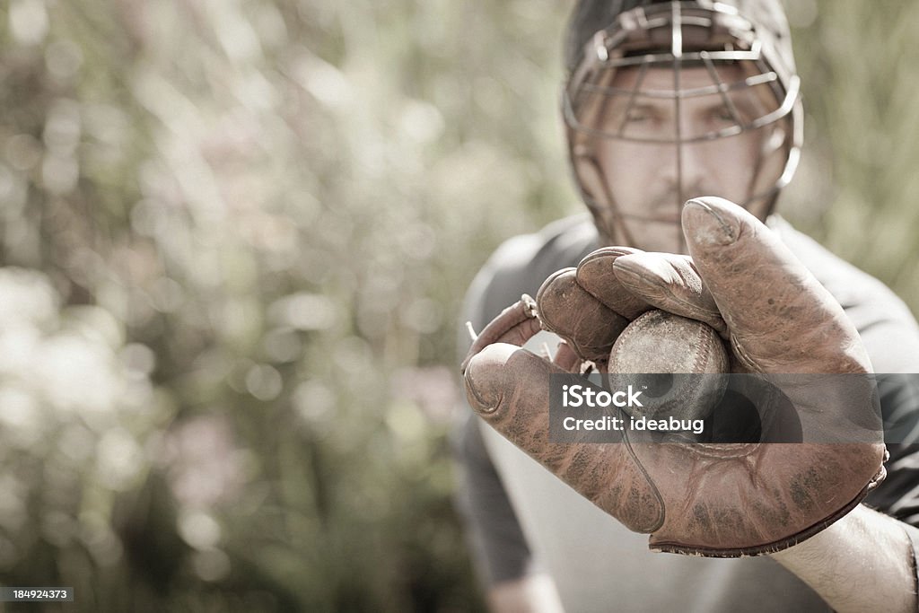 Vintage Baseball Player in Catching Stance with Ball "Color image of a vintage baseball player with ball and glove, in catching stance, with copy space.  Some desaturation and grain added for a vintage feel." Baseball Catcher Stock Photo