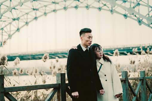 Asian young couple happily walking outdoors in winter