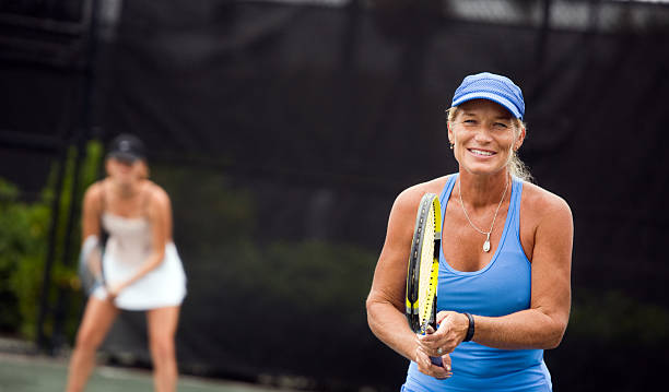 women's tennis doubles team mature woman preparing to play doubles in the volley position. tennis senior adult adult mature adult stock pictures, royalty-free photos & images