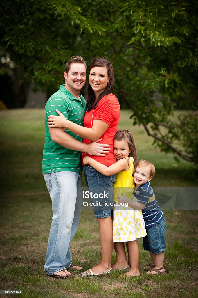 Família Jovem feliz abraçando um ao outro em ambiente ao ar livre - Foto de stock de 2-3 Anos royalty-free