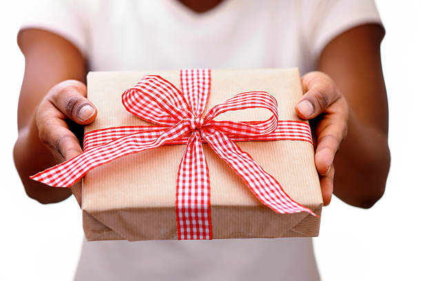 African woman giving a christmas present African woman giving a christmas present -shallow dof- XXXL Image hand holding gift stock pictures, royalty-free photos & images